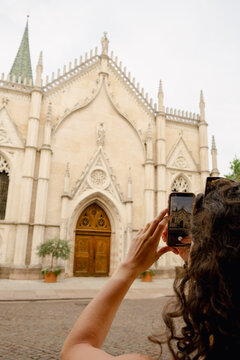 Woman photographing gothic church facade in Trento