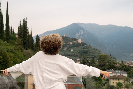 Anonymous Senior woman embracing mountain view from hotel terrace