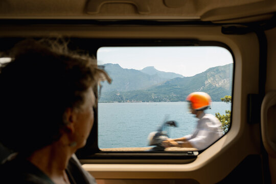Senior woman watching Lake Garda life through vehicle window, italy