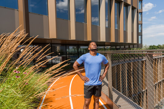 Athlete Resting On Running Track In Modern Architecture Background