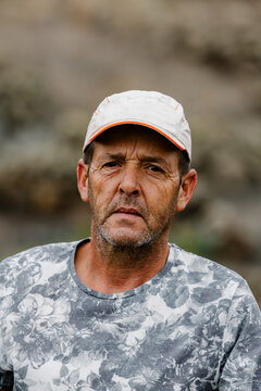 Close-up portrait of a serious mature man in a green vineyard.