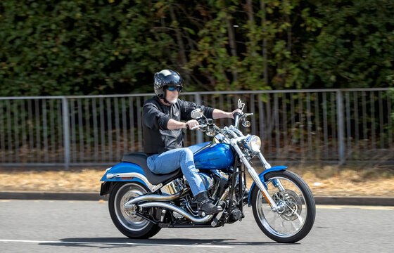 Milton Keynes,UK - Aug 2nd 2026:  Man riding a 2004 blue Harley Davidson fxstdi motorcycle driving on a British road