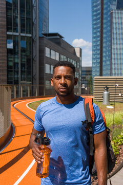 Man Holding Water Bottle on Urban Running Track in City