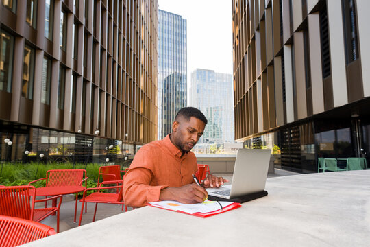 Man Works on Laptop Outdoors in a City Setting