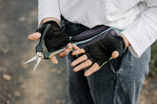 Close-up of gloved winery worker holding gardening tweezers.