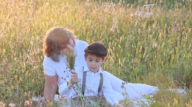 Sweet preteen child, boy, playing in a field on sunset with kite and old vingate car, walking with grandmother in the countryside