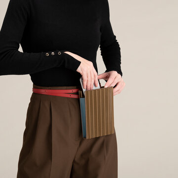 Hands Placing Phone Into Bag With Black Sweater