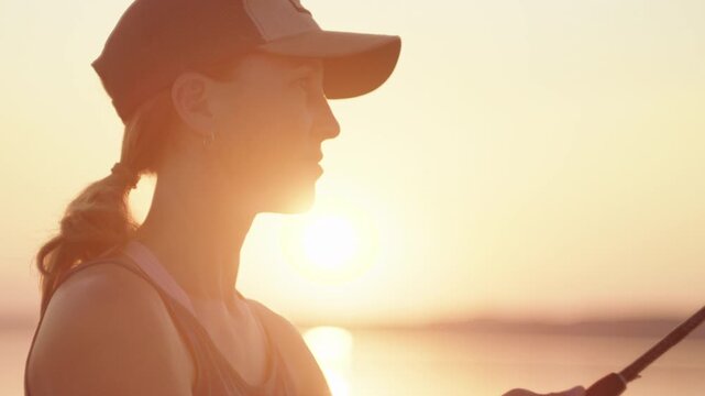 Young woman fishing on the river during sunset