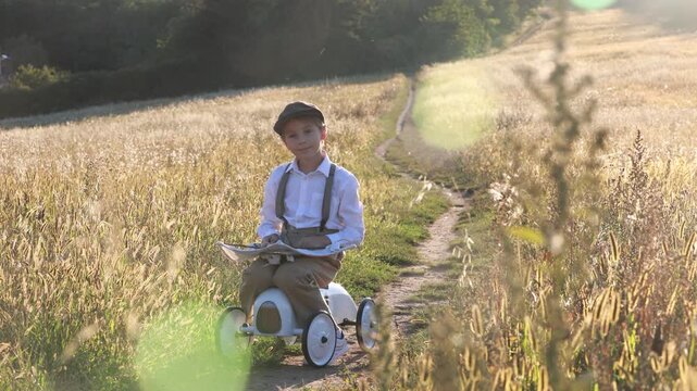 Sweet preteen child, boy, playing in a field on sunset with kite and old vingate car, walking with grandmother in the countryside