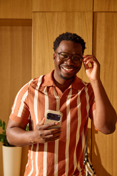 Happy man standing indoors with his phone in hand