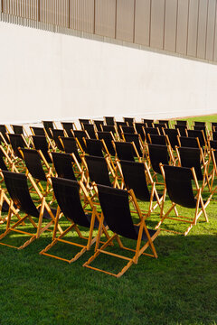 Rows of Empty Black Deck Chairs on a Green Lawn