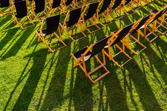 Empty Deck Chairs Casting Long Shadows on Grass