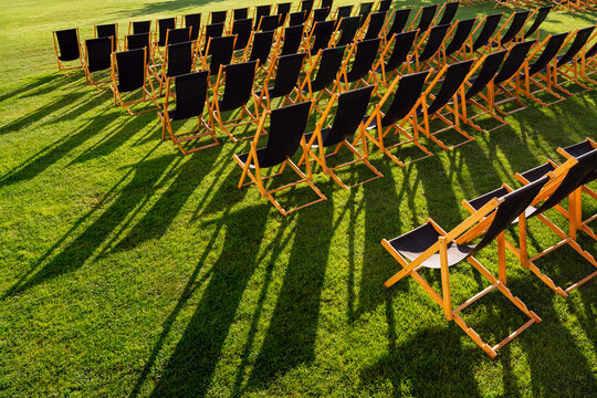 Empty Deck Chairs Casting Long Shadows on Grass
