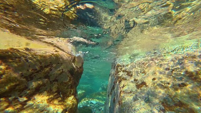 Underwater rocky crevice with rippling surface and sunlight