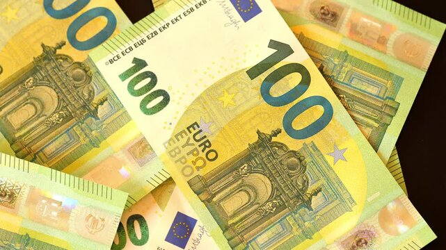 Green Euro 100 notes float freely. Pink Euro 500 notes lie nearby. Notes stack on black background. Denominations and security features clear. Dynamic finance stock footage