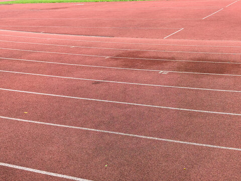 Close up of red running track with white lines. Athletic rubber surface background.