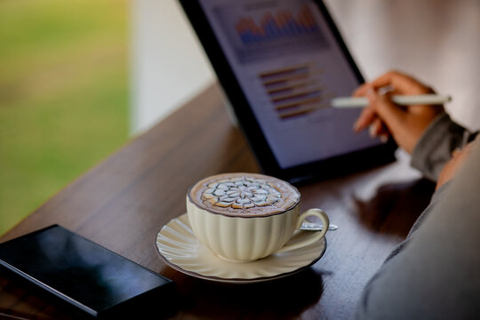 Business Professional Analyzing Data on Tablet with Coffee at Work