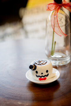 Cute Halloween Coffee Cup with Ghost Face and Latte Art on Wooden Table
