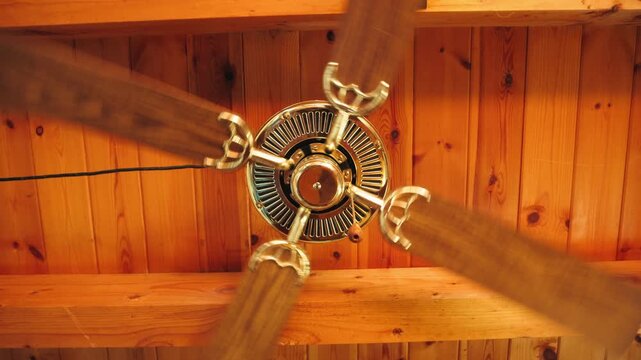 Ceiling fan spinning in a wooden country house interior, close-up of rotating fan blades, video footage. High quality 4k footage