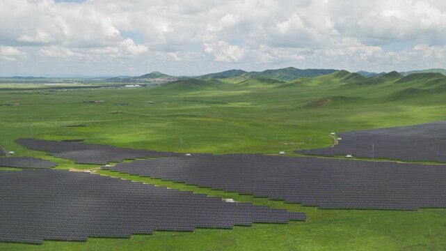High-Angle Aerial View of Solar PV Panel Array on Zoige Grassland Mountains, Aba, Sichuan: Renewable Clean Energy, Agrivoltaics, Green Hills, Blue Sky and Cloud Background