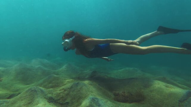 Young slim woman swims underwater, freediving and snorkeling in the sea near the coral reef near the island of Ilha Grande in Brazil