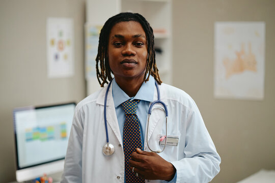 Portrait of young adult African American male pediatrician with stethoscope looking at camera in clinic office. Image suitable for pediatric healthcare marketing and medical services