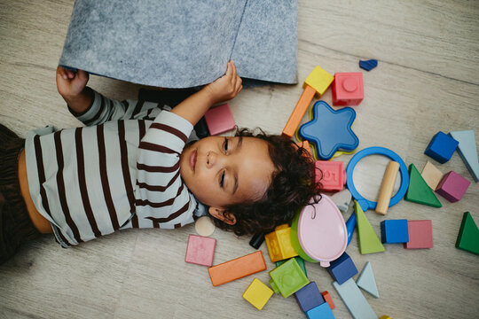 Top view of African American male toddler lying on floor playing with colorful sensory toys in pediatrician clinic. Useful for child healthcare and early development campaigns