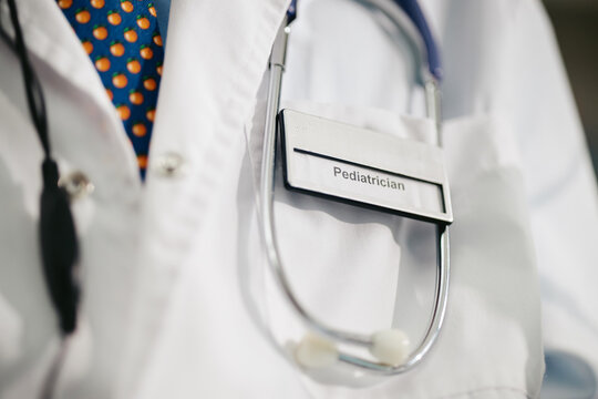 Close up shot of pediatrician wearing medical coat with badge and stethoscope, ready for patient examination. Image suitable for pediatric healthcare advertising and clinic websites