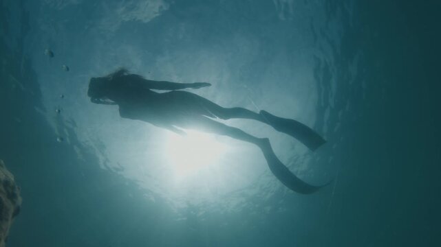 Young slim woman swims underwater, freediving and snorkeling in the sea near the coral reef near the island of Ilha Grande in Brazil