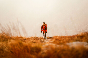 Fototapeta premium Hiker in misty autumn landscape, vibrant orange hues
