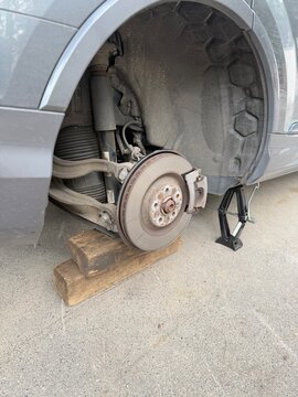 Car Brake and Suspension Repair with Jack and Wooden Blocks Support
