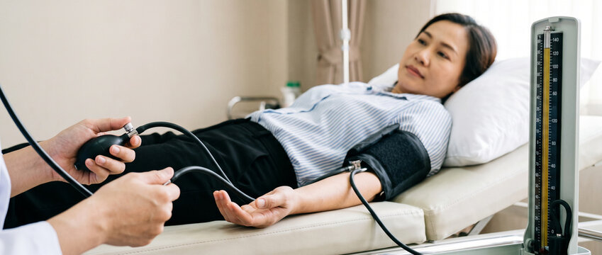 Close-up hands of nurse measuring blood pressure of patient