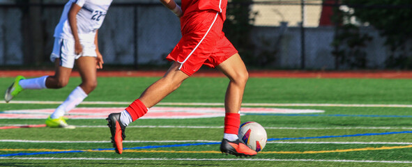 Fototapeta premium Soccer player dribbling the ball running down the field