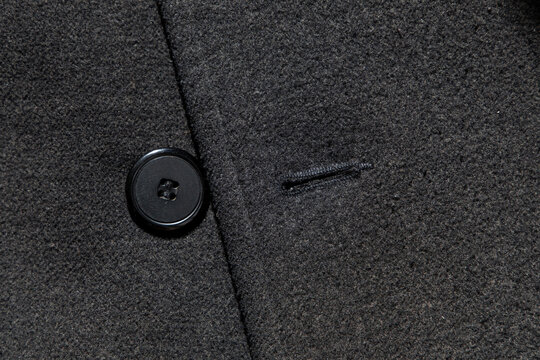 Close-up view of a black coat with a button and buttonhole displayed for detail