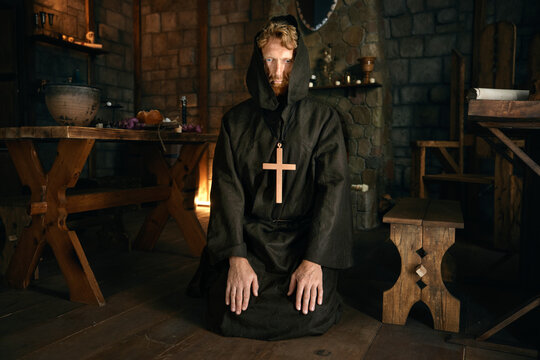 Medieval monk praying to God looking upward in monastery