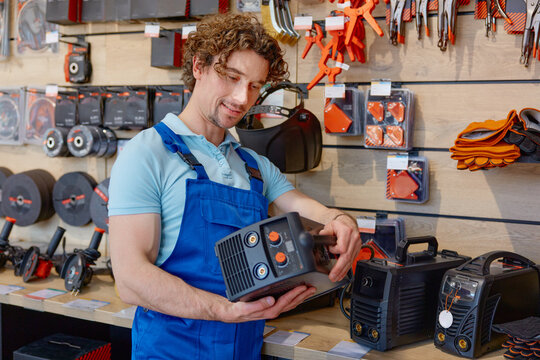 Man worker in overalls choosing welding machine at hardware store