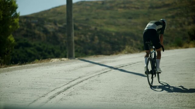 Cyclist Riding Road Bike Uphill On Scenic Mountain Highway During Intense Athletic Training Session