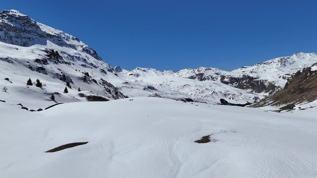 snowfield stretches across high alpine bowl beneath rocky ridgeline snowcapped peaks scattered pine trees trail signpost marks route near julier pass albula alps graubunden switzerland engadin border
