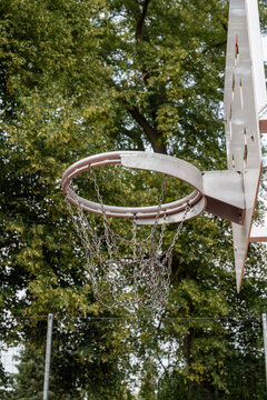 An old basketball hoop with a frayed net hangs suspended
