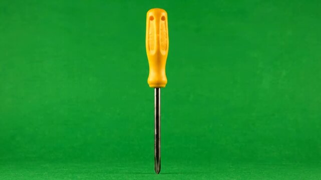 Yellow handled screwdriver tool standing vertically isolated on a bright green chroma key background for home repair