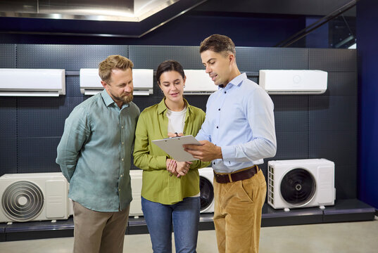 Salesman consultation with couple on airconditioner choosing. In a retail store customers get expert advice. Details cover models features and pricing. Clear retail AC purchase concept.