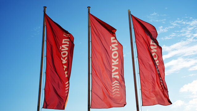 Three Red Flags of Lukoil, a Russian Oil Company, Against a Blue Sky