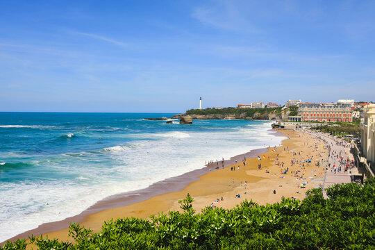 View of sandy beach and white lighthouse at Grande Plage in Biarrits, France