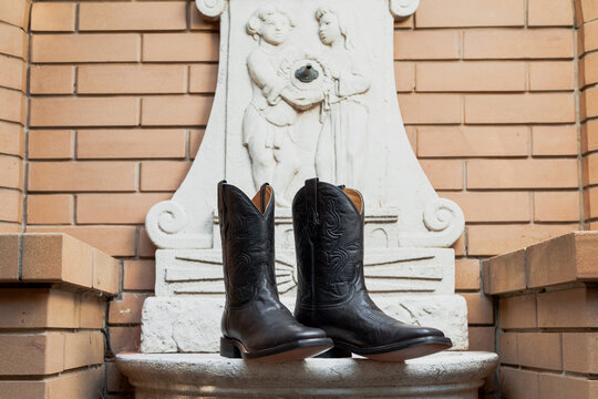 Embossed black leather boots against a white wall