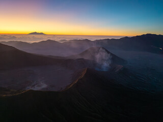 Aerial sunset panorama of Mount Bromo volcanic landscape, layered ridges, drifting mist, and cloud filled horizons in Indonesia. © Cloudyew