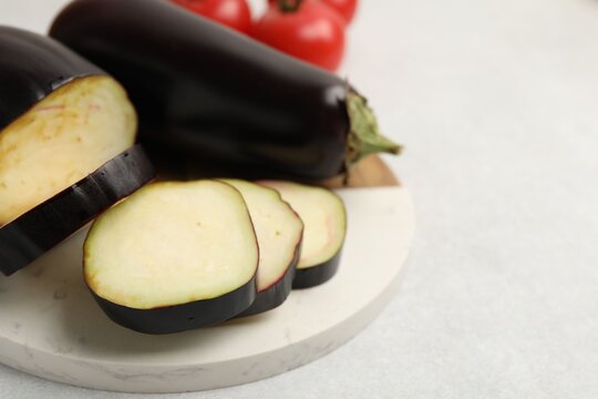 Fresh raw eggplants and tomatoes on light grey table, closeup. Space for text