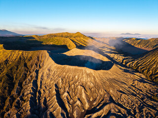 Golden sun bathes volcanic Mount Bromo peaks in warm light. Rugged terrain reveals deep canyons © Cloudyew
