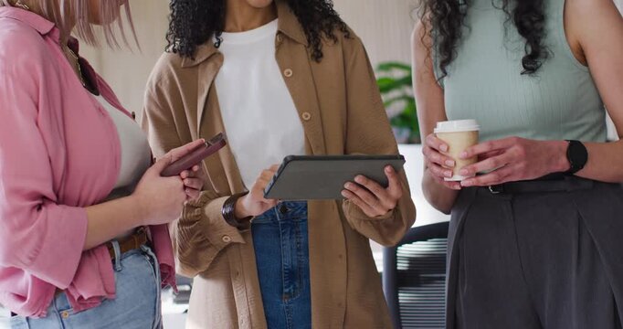 African American team meeting at tablet in office, woman tapping, peers pointing with phone and cup