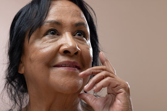 Senior African American woman touching cheek with manicured right hand in studio with soft lighting