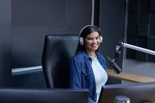 African American woman wearing denim shirt recording podcast at studio with headphones, boom mic
